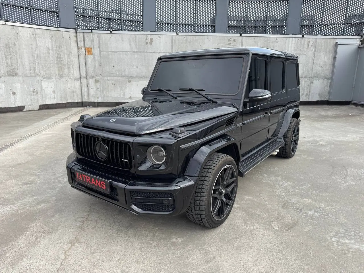 Чорний Mercedes-Benz G63 AMG 2013 з табличкою KTRANS на бетонному даху паркінгу